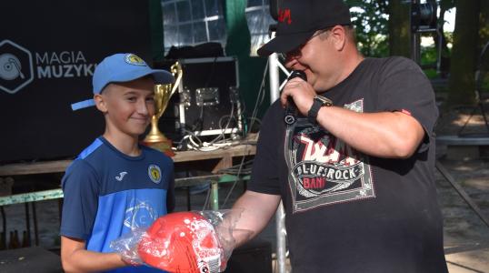 Sołtys Osolina Marcin Tyrała wręczający dzieciom nagrody za żonglerkę piłką nożną